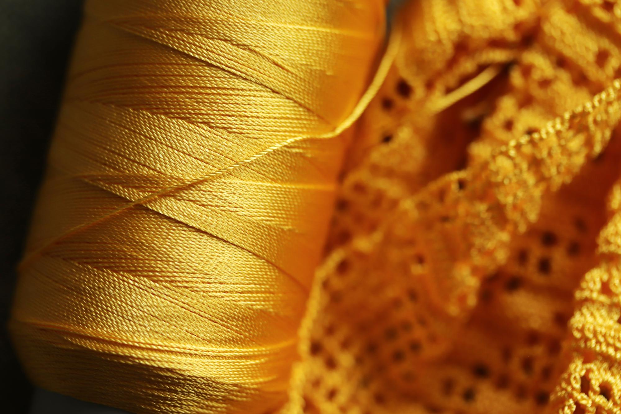 Hand stitching a gold thread motif on black linen